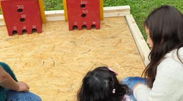Juego tradicional con bolitas de vidrio que deben entrar en la casillas